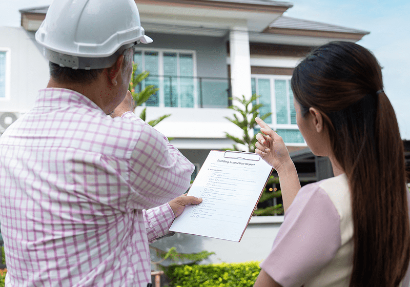 Inspector and woman discussing house construction plans.